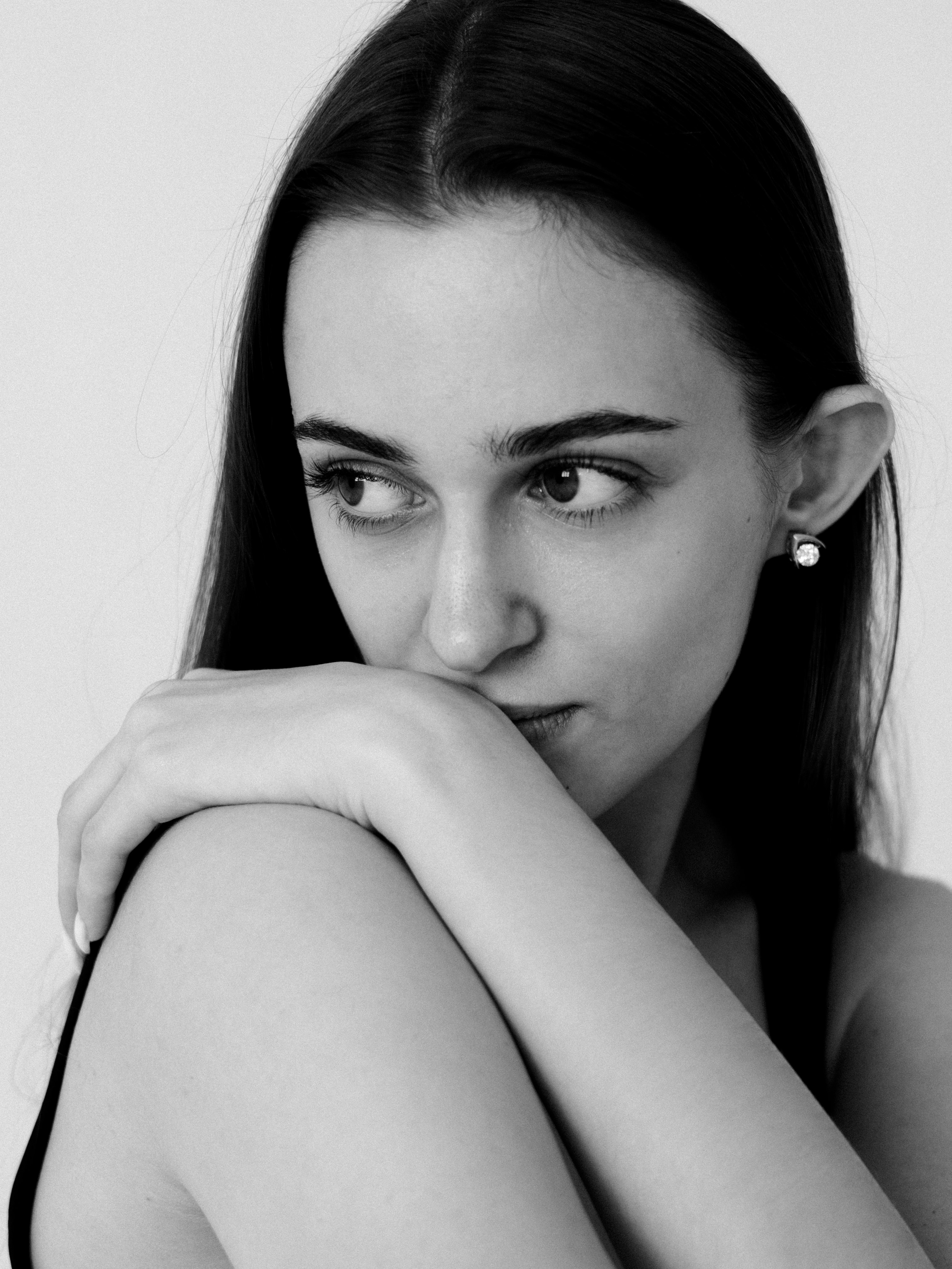 Black-and-white close portrait of a dark-haired woman resting her chin on her arm